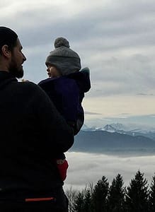 A man holding a child on top of a mountain.