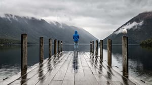 A man standing on a dock in a rainy day.