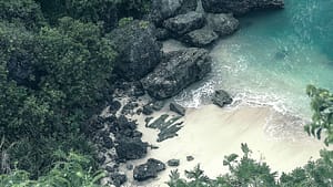An aerial view of a beach surrounded by rocks and trees.
