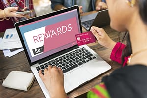 A woman is using a laptop to explore the Benefits of Credit Card Rewards.