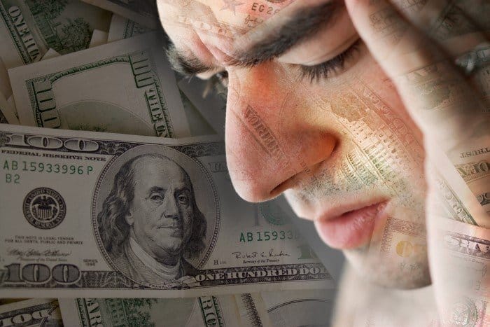 A man with his head in front of a pile of money, finally starting to stop worrying about money.