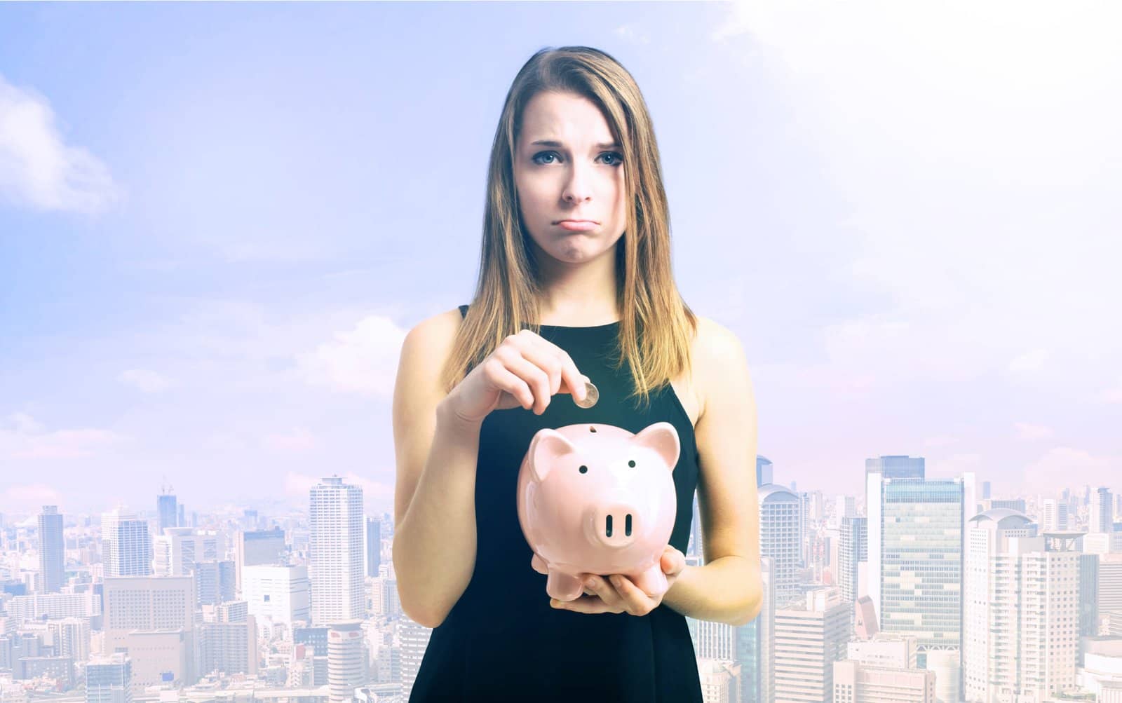 Photo of young woman in black dropping coins in a piggy bank