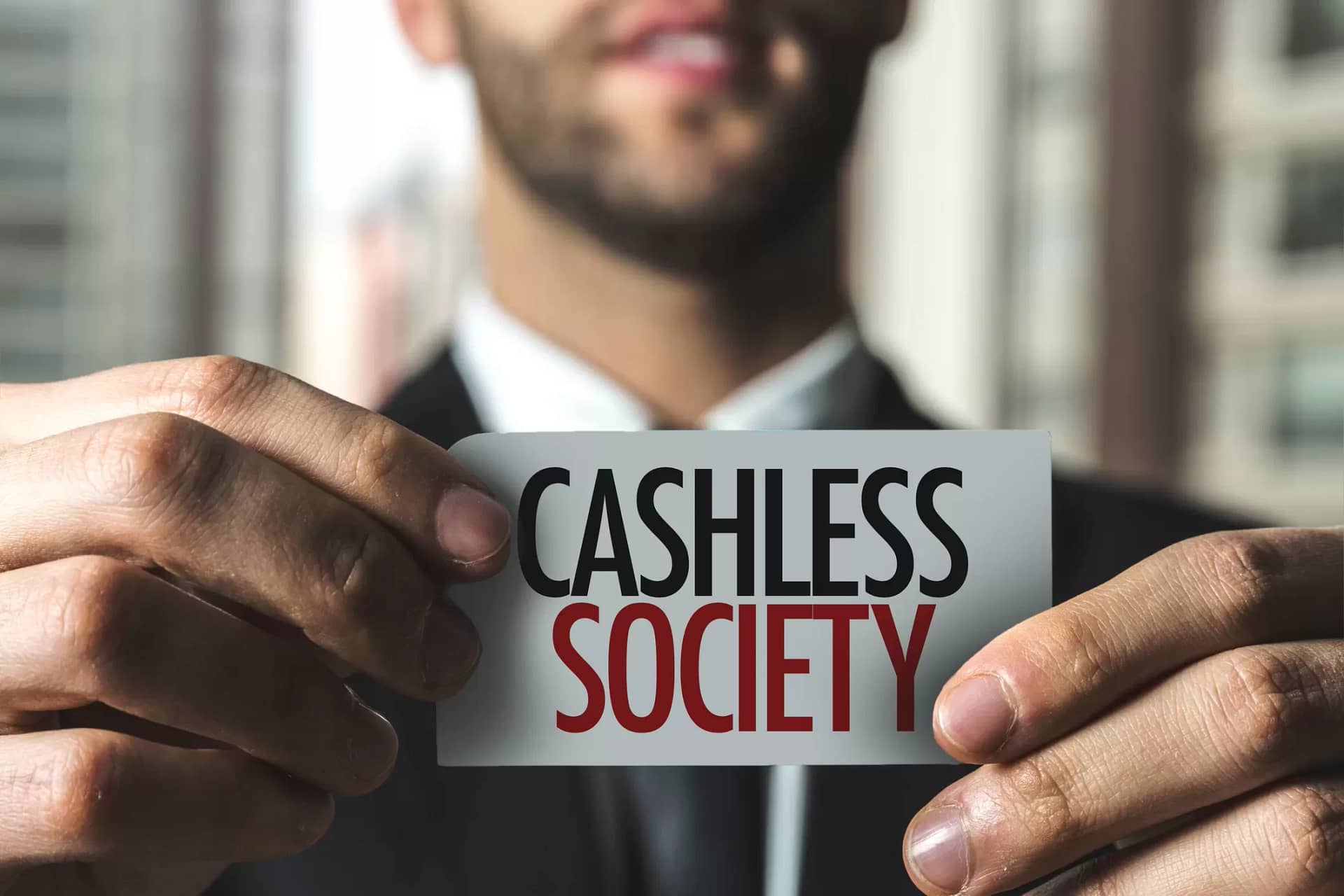 A man holding up a card that says cashless society.